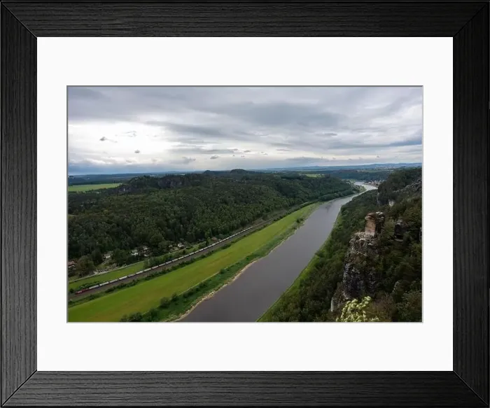 Framed Print : A river with a train passing by. The train is carrying a lot of cars. The sky is cloudy Framed Print : A river with a train passing by. The train is carrying a lot of cars. The sky is cloudy