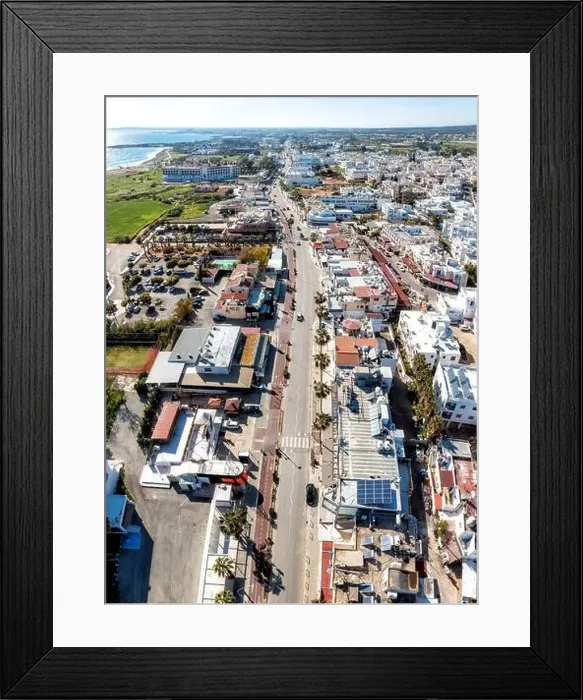Framed Print : Aerial view of a city center of Ayia Napa with an empty street running through it towards the sea on a sunny day. Cyprus