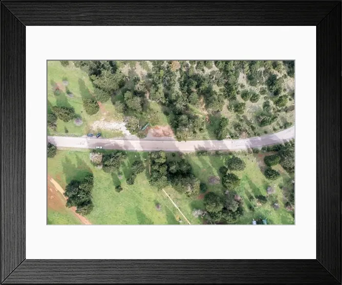 Framed Print : Road and a forest glade among fir trees in mountains, aerial drone view. Spring season Framed Print : Road and a forest glade among fir trees in mountains, aerial drone view. Spring season
