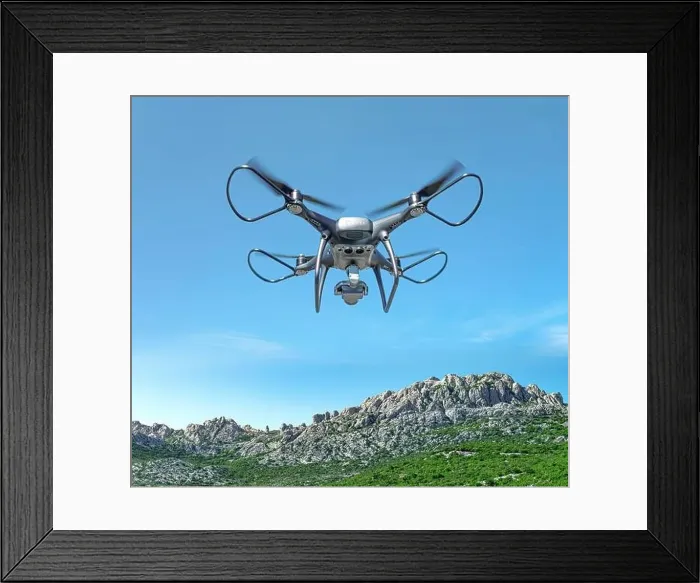 Framed Print : A drone with a camera flies against the backdrop of a mountain landscape Framed Print : A drone with a camera flies against the backdrop of a mountain landscape