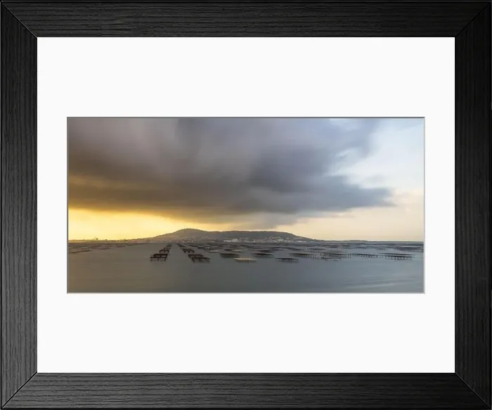 Framed Print : Mont Saint Clair and the Thau lagoon, with its oyster tables, under a stormy sky, in Hérault, Occitanie, France Framed Print : Mont Saint Clair and the Thau lagoon, with its oyster tables, under a stormy sky, in Hérault, Occitanie, France