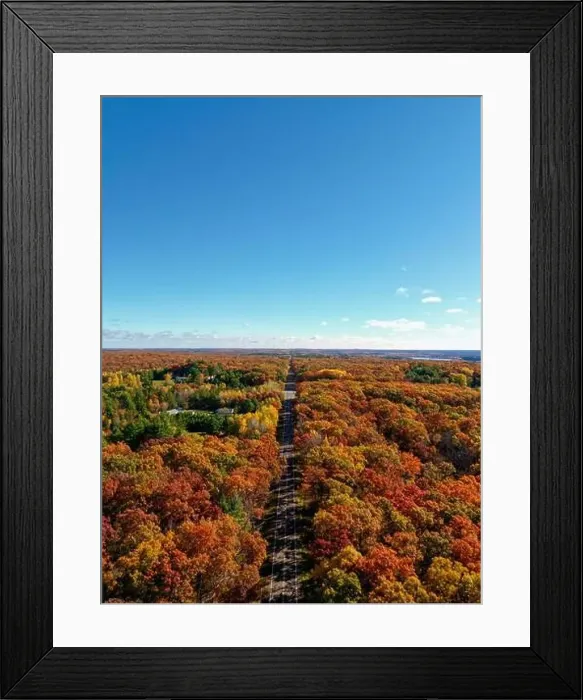 Framed Print : A stunning aerial view of a peaceful road stretching through a forest ablaze with vibrant autumn colors Framed Print : A stunning aerial view of a peaceful road stretching through a forest ablaze with vibrant autumn colors