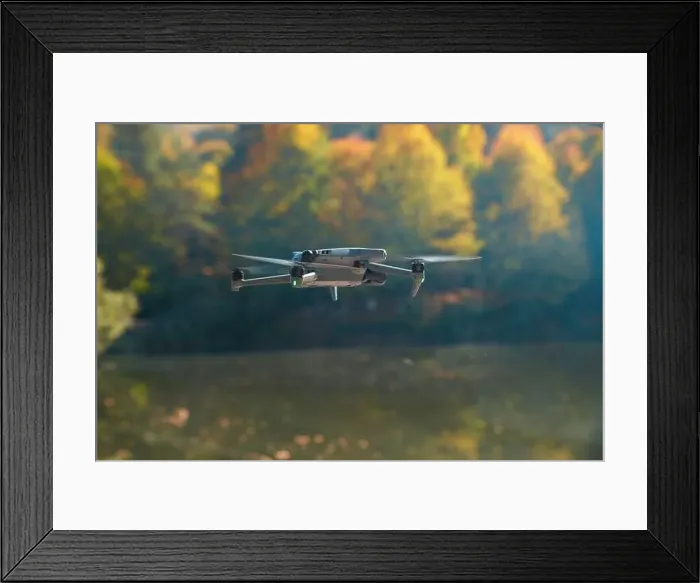 Framed Print : A drone is flying over a lake with trees in the background Framed Print : A drone is flying over a lake with trees in the background