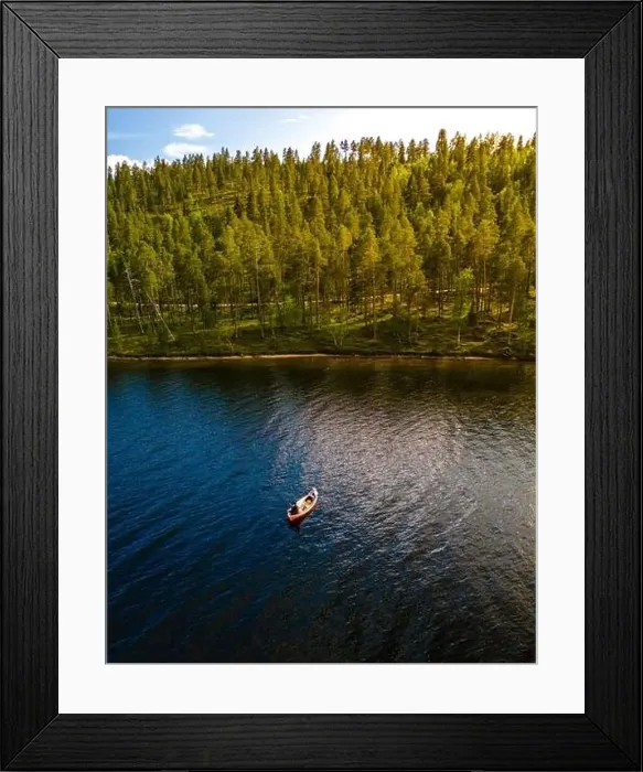 Framed Print : A small boat drifts peacefully on the surface of a tranquil lake, surrounded by a lush forest in Finnish Lapland Framed Print : A small boat drifts peacefully on the surface of a tranquil lake, surrounded by a lush forest in Finnish Lapland