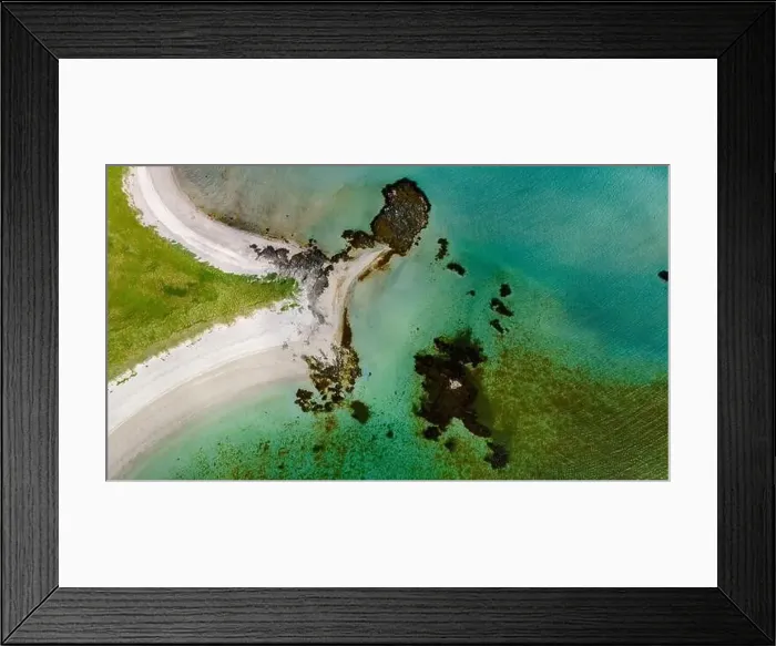 Framed Print : An aerial view of a pristine beach curving around a rocky outcropping Framed Print : An aerial view of a pristine beach curving around a rocky outcropping