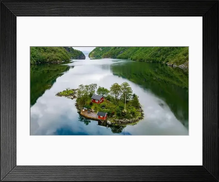 Framed Print : A small island with two red cabins nestled among green trees is surrounded by calm Framed Print : A small island with two red cabins nestled among green trees is surrounded by calm
