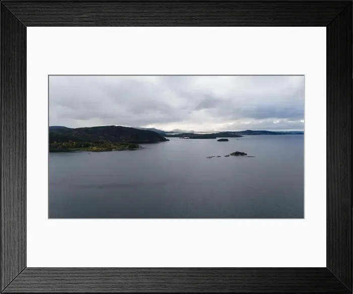 Framed Print : A serene landscape featuring a calm fjord surrounded by forested hills under a cloudy sky Framed Print : A serene landscape featuring a calm fjord surrounded by forested hills under a cloudy sky