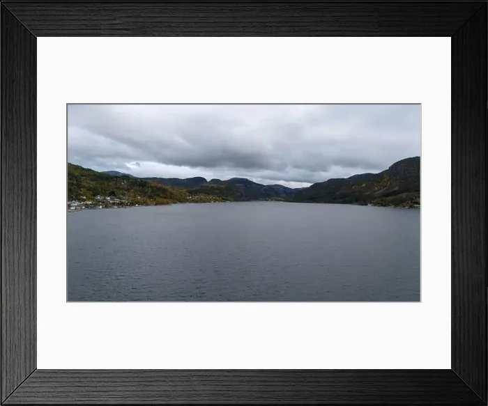 Framed Print : A serene landscape featuring a calm fjord surrounded by forested hills under a cloudy sky Framed Print : A serene landscape featuring a calm fjord surrounded by forested hills under a cloudy sky