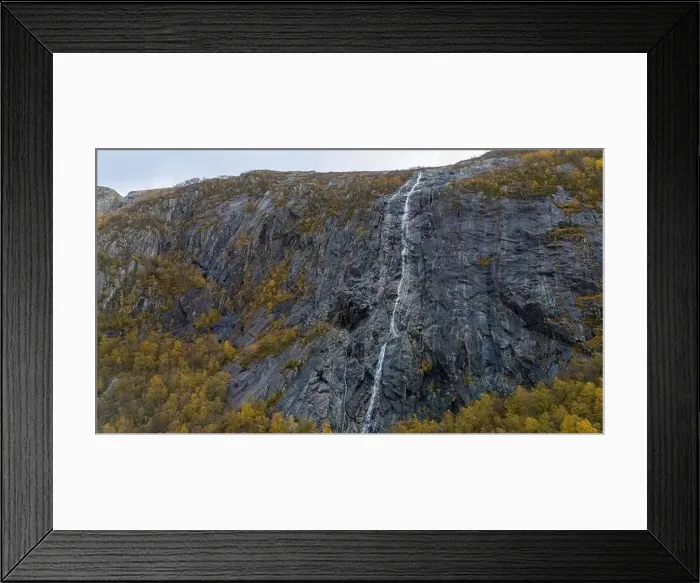 Framed Print : A tall, narrow waterfall cascading down a rugged, rocky cliff surrounded by autumn foliage Framed Print : A tall, narrow waterfall cascading down a rugged, rocky cliff surrounded by autumn foliage