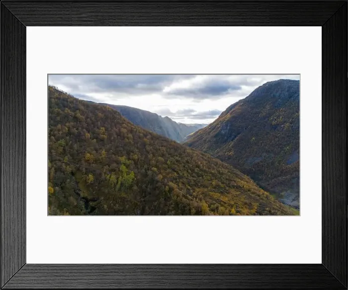 Framed Print : Aerial view of a scenic valley surrounded by forested mountains under a cloudy sky Framed Print : Aerial view of a scenic valley surrounded by forested mountains under a cloudy sky