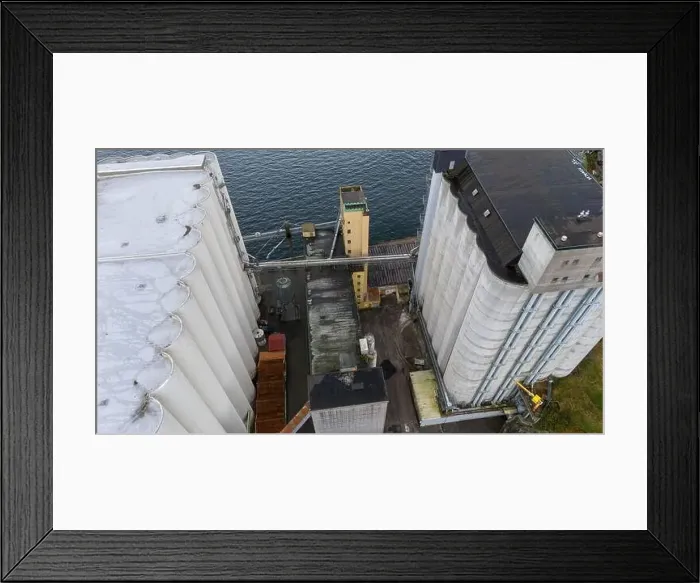 Framed Print : Aerial view of industrial silos and buildings near a body of water Framed Print : Aerial view of industrial silos and buildings near a body of water