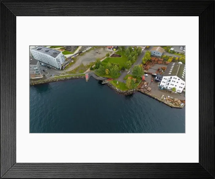 Framed Print : Aerial view of a coastal industrial area with buildings, trees, and a dock