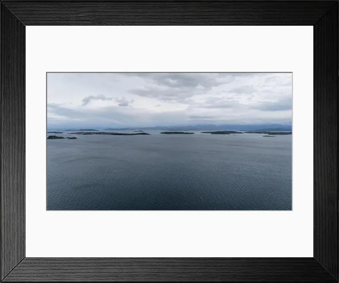Framed Print : Aerial view of a calm sea with scattered small islands under a cloudy sky Framed Print : Aerial view of a calm sea with scattered small islands under a cloudy sky