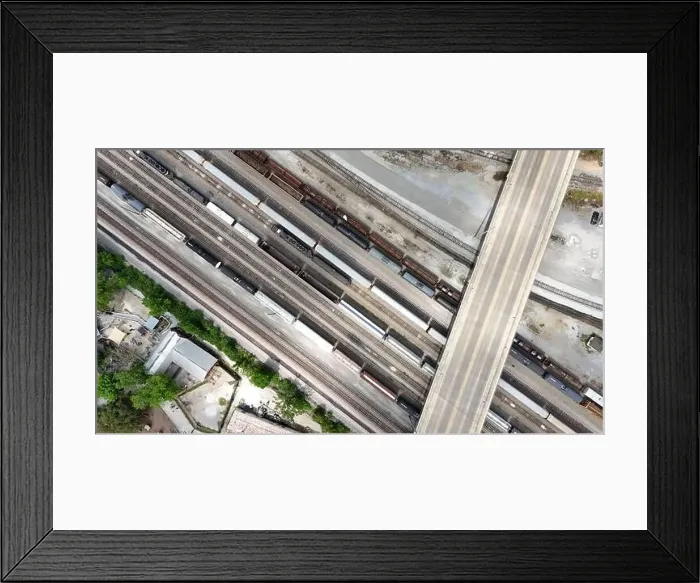 Framed Print : An overhead drone shot captures the railroad tracks as a train passes through Framed Print : An overhead drone shot captures the railroad tracks as a train passes through