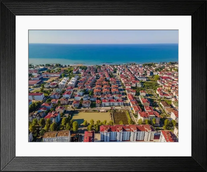 Framed Print : A city street view with a large water field in the middle. The field is surrounded by buildings and trees Framed Print : A city street view with a large water field in the middle. The field is surrounded by buildings and trees
