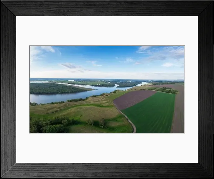 Framed Print : Aerial landscape showing a scenic river winding through lush forests and farmlands, with open fields and a clear sky Framed Print : Aerial landscape showing a scenic river winding through lush forests and farmlands, with open fields and a clear sky