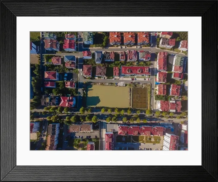 Framed Print : A city street view with a large water field in the middle. The field is surrounded by buildings and trees Framed Print : A city street view with a large water field in the middle. The field is surrounded by buildings and trees