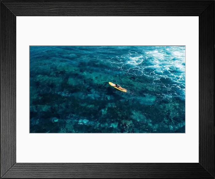 Framed Print : Woman rowing on surfboard in blue ocean. Drone view of woman during surfing Framed Print : Woman rowing on surfboard in blue ocean. Drone view of woman during surfing