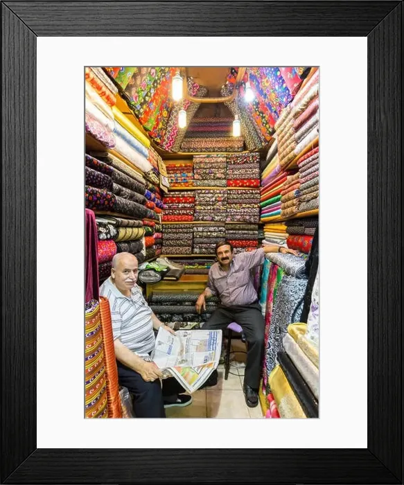 Framed Print : Sellers (vendors) of traditional Turkish fabrics seated in their shop reading a newspaper Framed Print : Sellers (vendors) of traditional Turkish fabrics seated in their shop reading a newspaper