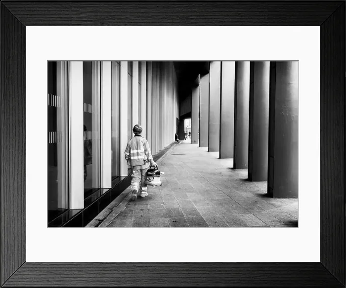 Framed Print : London black and white street photography: Workman carrying Numatic Henry vacuum cleaner in street