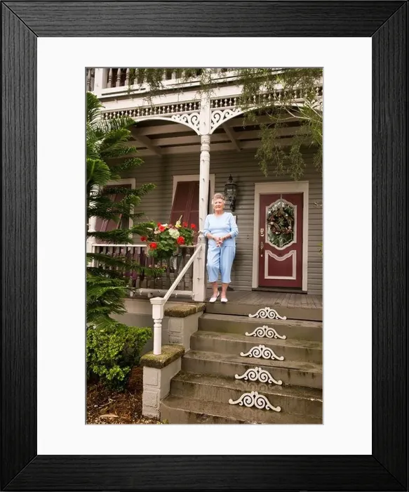 Framed Print : Senior woman standing on front porch of house Framed Print : Senior woman standing on front porch of house