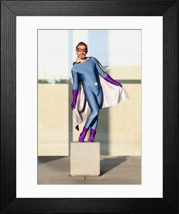 Framed Print : Portrait of superhero holding cape while standing on concrete against glass wall