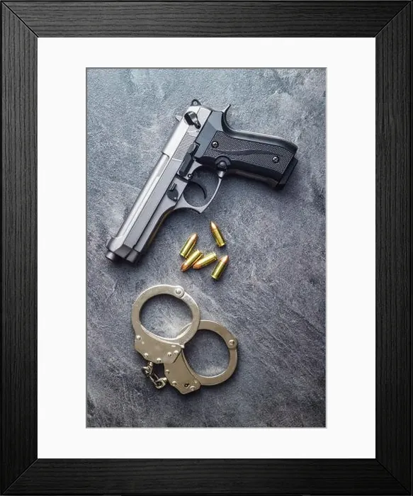 Framed Print : Pistol bullets, handgun and handcuffs on black table Framed Print : Pistol bullets, handgun and handcuffs on black table