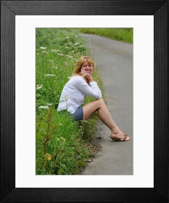 Framed Print : Mature woman wearing a white shirt and short skirt sitting on the roadside Framed Print : Mature woman wearing a white shirt and short skirt sitting on the roadside