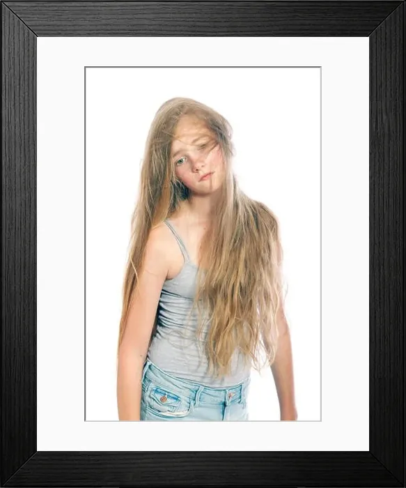 Framed Print : young and sad teen girl hides behind blond wavy hair against white studio background Framed Print : young and sad teen girl hides behind blond wavy hair against white studio background