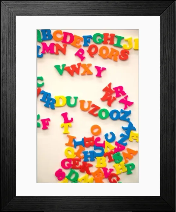 Framed Print : A jumble of colorful magnetic alphabet letters on a white board in a classroom Framed Print : A jumble of colorful magnetic alphabet letters on a white board in a classroom