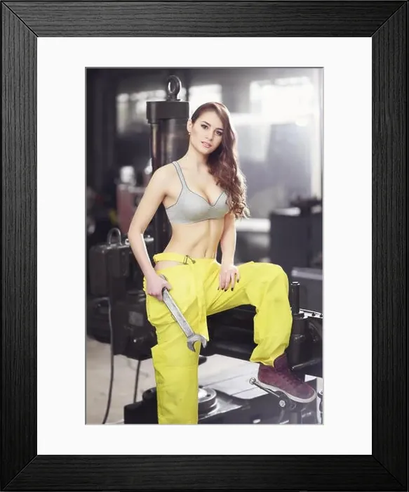 Framed Print : Nice sexy woman mechanic holding wrench. Girl weared in yellow work overalls and grey uplift standing over the factory Framed Print : Nice sexy woman mechanic holding wrench. Girl weared in yellow work overalls and grey uplift standing over the factory