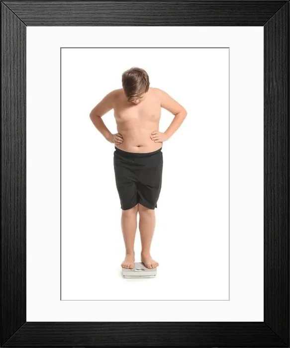 Framed Print : Overweight boy standing on scales against white background Framed Print : Overweight boy standing on scales against white background