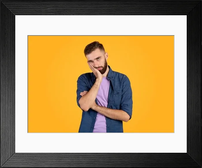 Framed Print : Portrait of bored Caucasian guy leaning on palm and looking at camera on orange studio background Framed Print : Portrait of bored Caucasian guy leaning on palm and looking at camera on orange studio background