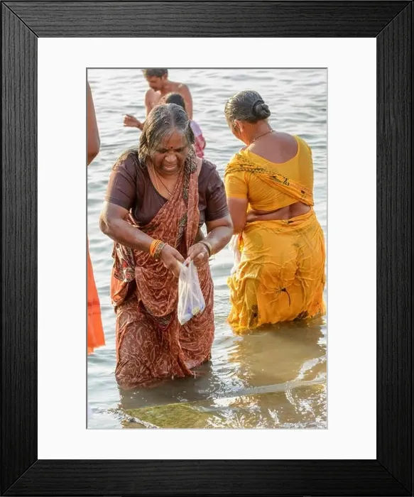 Framed Print : An Indian Hindu woman wearing a sari performs an early morning bathing ritual in the River Ganges in Varanasi