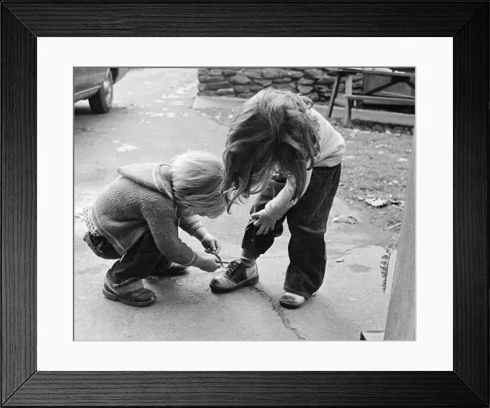Framed Print : 1970s 1970s BLOND BOY BENDING OVER HELPING GIRL TIE HER SHOE