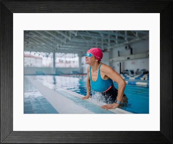 Framed Print : Happy senior woman getting out of the swimming pool indoors Framed Print : Happy senior woman getting out of the swimming pool indoors