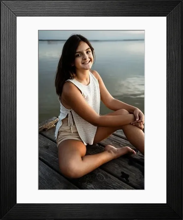 Framed Print : Happy girl sitting on jetty against lake Framed Print : Happy girl sitting on jetty against lake