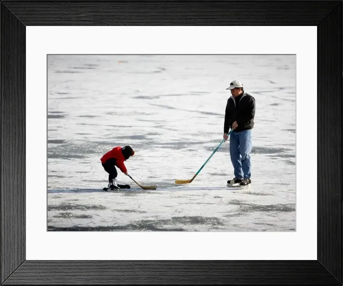 Framed Print : Father and son playing ice hockey on a frozen lake Framed Print : Father and son playing ice hockey on a frozen lake