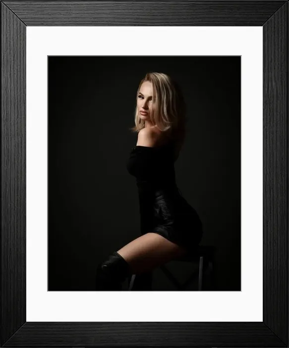 Framed Print : Sexy blonde woman vamp in black leather shorts, pullover and boots is sitting sideways looking at camera flirting Framed Print : Sexy blonde woman vamp in black leather shorts, pullover and boots is sitting sideways looking at camera flirting