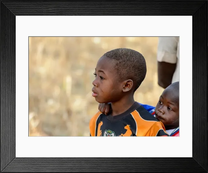 Framed Print : KOUTAMMAKOU, TOGO - JAN 13, 2017: Unidentified Togolese little boy carries his brother on his back in the village Framed Print : KOUTAMMAKOU, TOGO - JAN 13, 2017: Unidentified Togolese little boy carries his brother on his back in the village