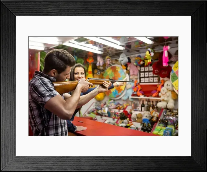 Framed Print : Young fun couple playing shooting games at amusement park