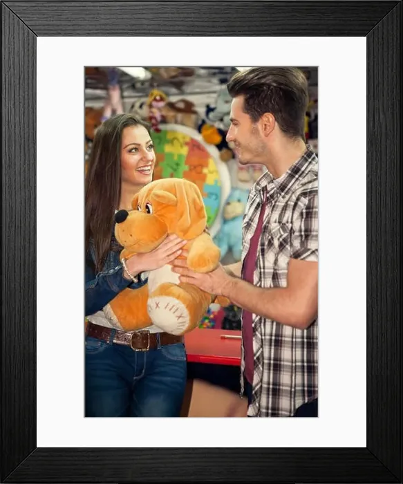Framed Print : Young couple playing shooting games while visiting an amusement park Framed Print : Young couple playing shooting games while visiting an amusement park