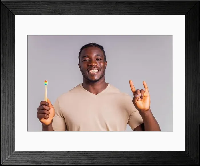 Framed Print : afrian american man holding colorful rainbow toothbrush in gray backgroung