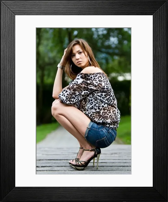 Framed Print : Young woman wearing hot pants, a leopard-print top and high heels, posing crouching down Framed Print : Young woman wearing hot pants, a leopard-print top and high heels, posing crouching down