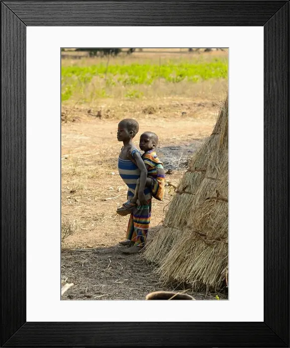 Framed Print : GHANI, GHANA - JAN 14, 2017: Unidentified Ghanaian little girl carries a baby on her back in the Ghani village Framed Print : GHANI, GHANA - JAN 14, 2017: Unidentified Ghanaian little girl carries a baby on her back in the Ghani village