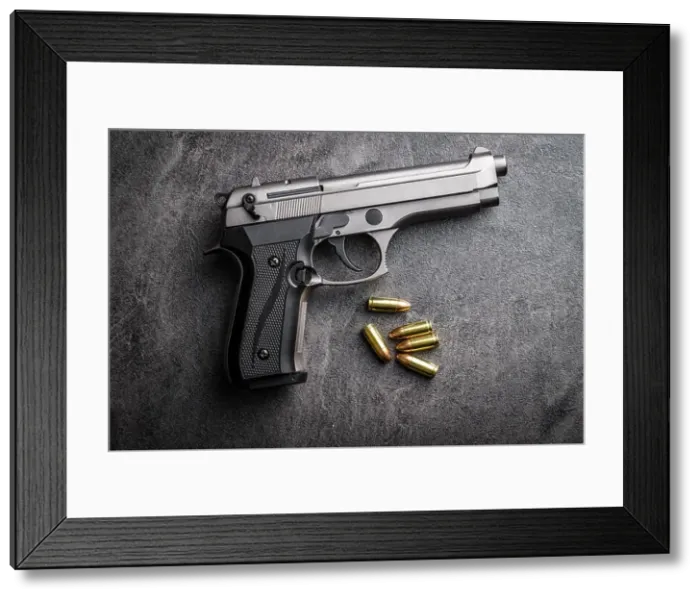 Framed Print : 9mm pistol bullets and handgun on black table Framed Print : 9mm pistol bullets and handgun on black table