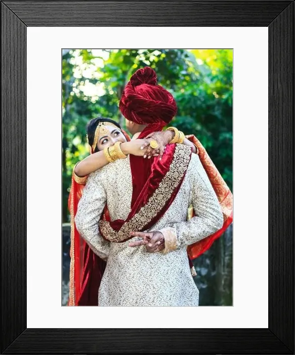 Framed Print : Indian wedding couple hugging and groom showing victory sign with green bokeh background Framed Print : Indian wedding couple hugging and groom showing victory sign with green bokeh background