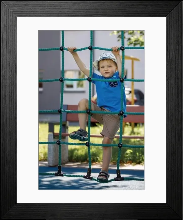 Framed Print : Portrait of cute smiling boy climbing up the rope net he look at camera Framed Print : Portrait of cute smiling boy climbing up the rope net he look at camera