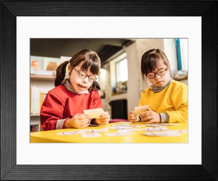 Framed Print : Sisters with Down syndrome playing with cards together Framed Print : Sisters with Down syndrome playing with cards together