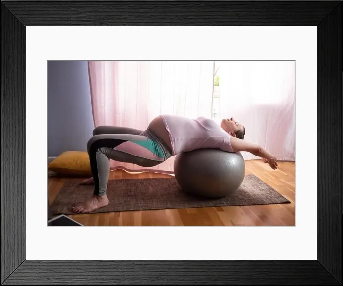 Framed Print : young pregnant caucasian woman practices yoga at home. Online lessong on laptop Framed Print : young pregnant caucasian woman practices yoga at home. Online lessong on laptop
